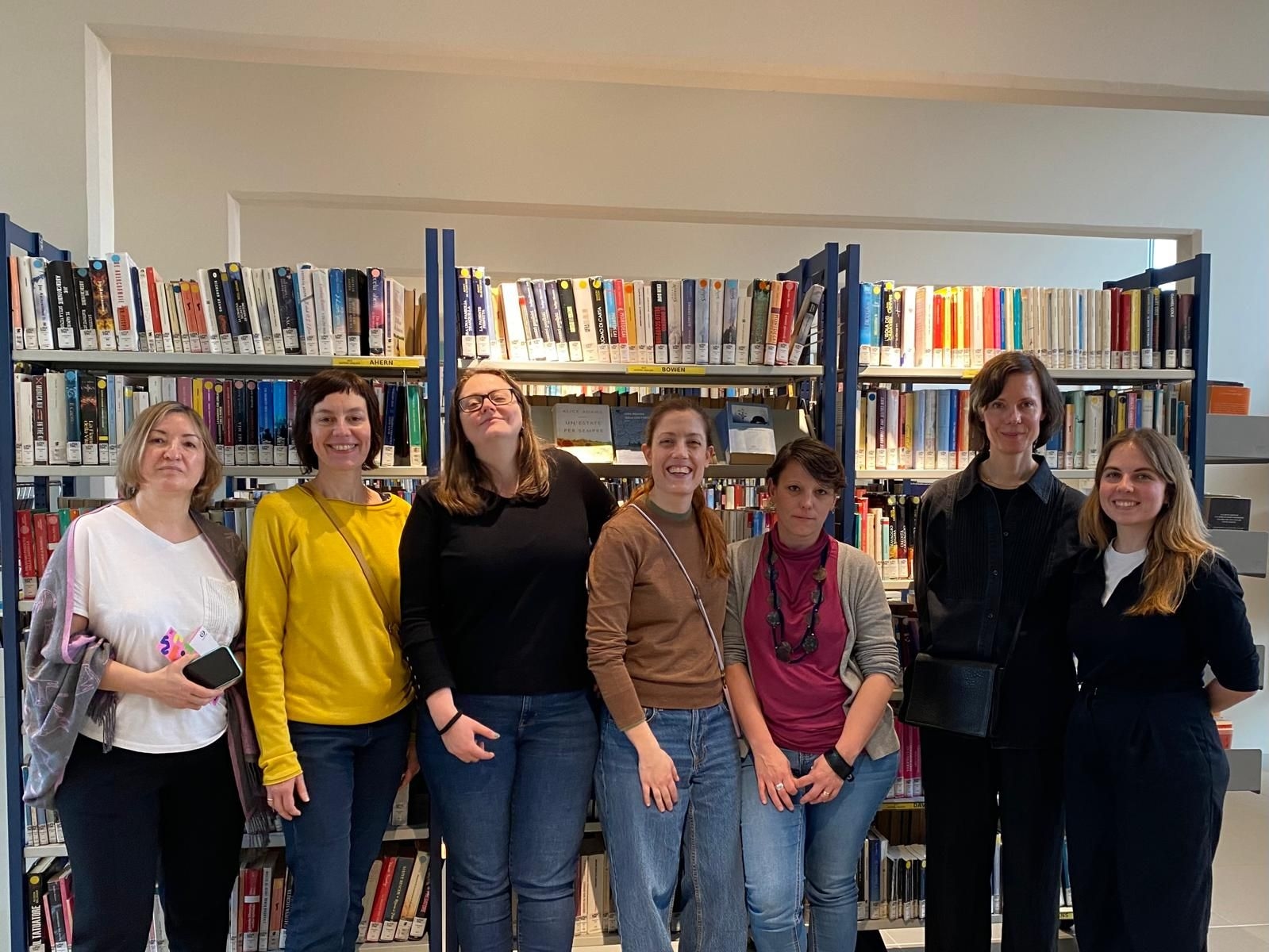 Participants of the DigLib project kick-off meeting standing in front of a bookshelf, smiling in an informal and collaborative setting.