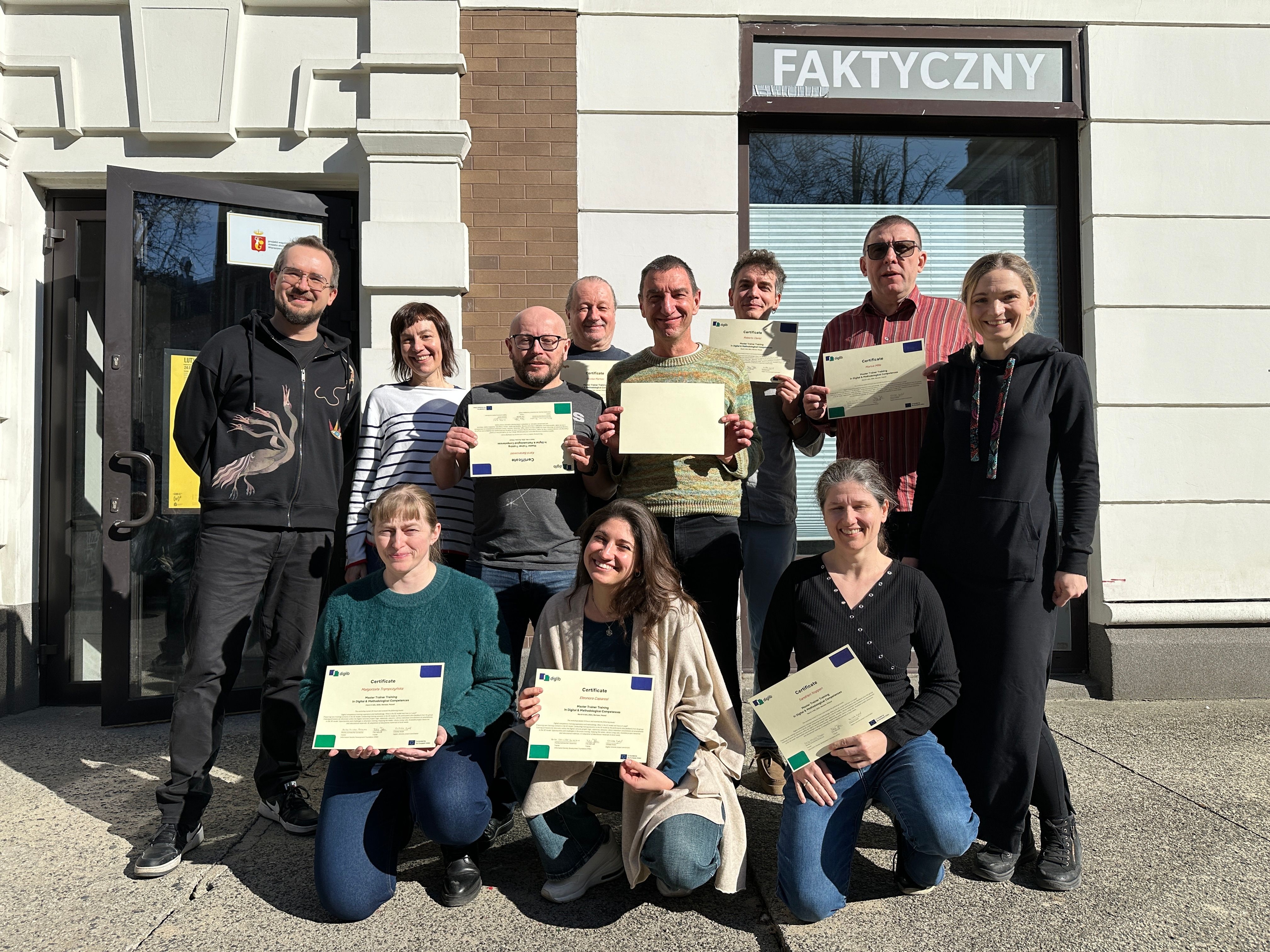 DigLib trainer team posing in Warsaw, holding their certificates of completion after the train-the-trainers workshop.