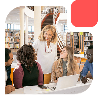 Group of adults discussing around a laptop in a modern library, guided by a trainer.